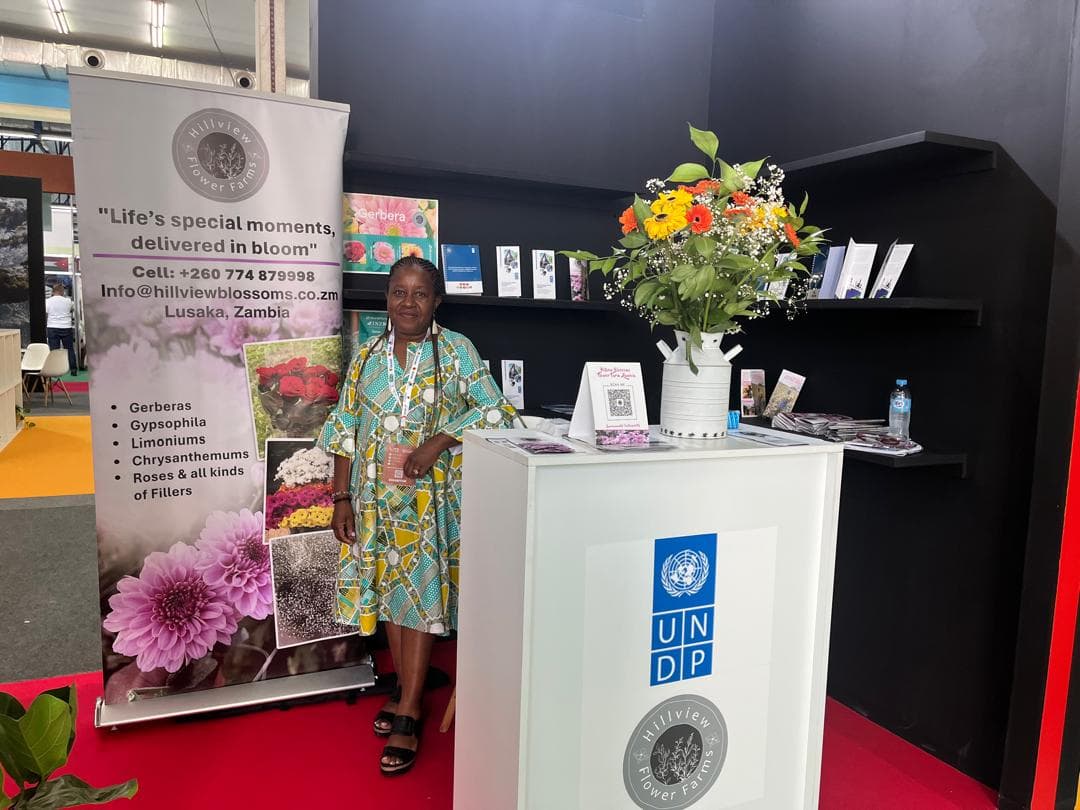 The Hillview Blossoms stand at IATF2025 in Algiers, with the farm's banner and a fresh bouquet on the UNDP podium