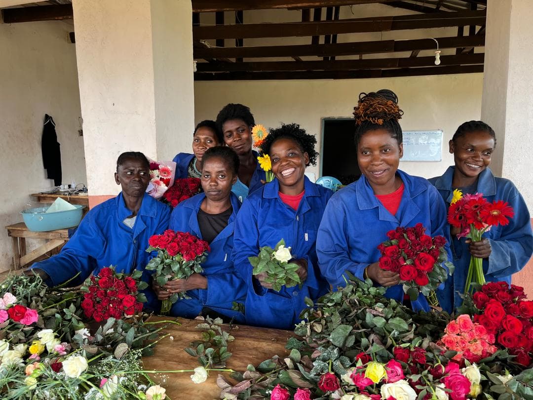 The packhouse team holding bunches of red roses